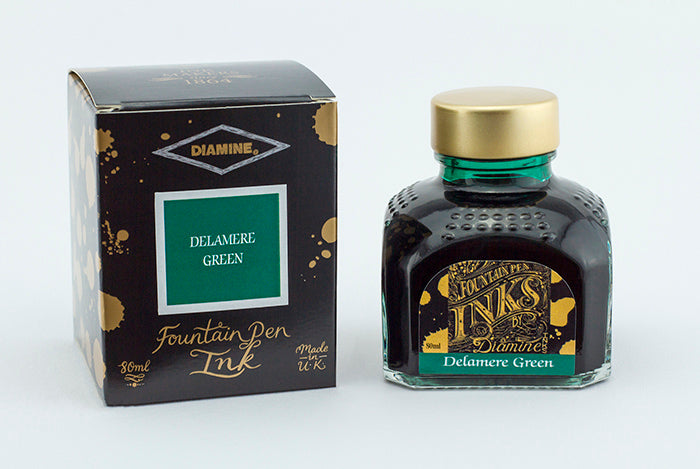 A glass bottle of 80ml Diamine Delamere Green fountain pen ink next to its packaging box, in front of a white background.