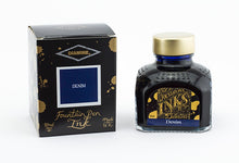 Load image into Gallery viewer, A glass bottle of 80ml Diamine Denim fountain pen ink next to its packaging box, in front of a white background.
