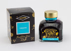 A glass bottle of 80ml Diamine Turquoise fountain pen ink next to its packaging box, in front of a white background.