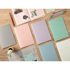 Group of different colour Midori Notebooks on table.