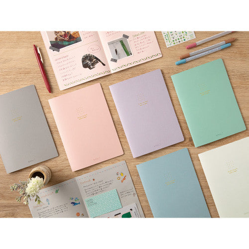 Group of different colour Midori Notebooks on table.