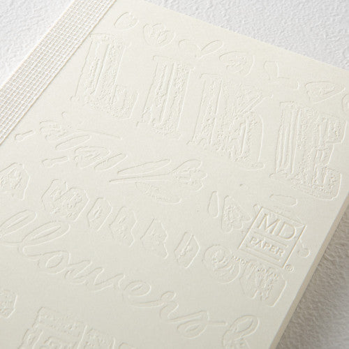 Detailed close up of 15th anniversary limited edition MD Notebook with embossed Holly Wales design, on a white background.