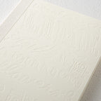Detailed close up of 15th anniversary limited edition MD Notebook with embossed Holly Wales design, on a white background.