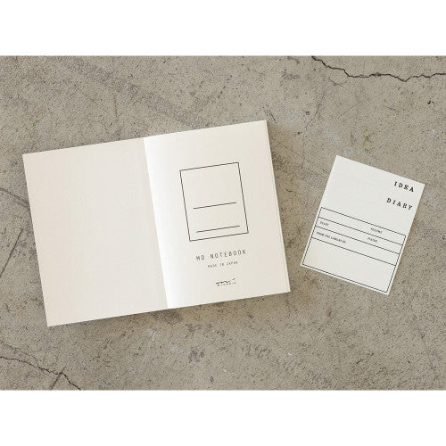 Open on first page 15th anniversary limited edition MD Notebook with embossed Holly Wales design, on a concrete background.