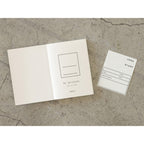 Open on first page 15th anniversary limited edition MD Notebook with embossed Holly Wales design, on a concrete background.