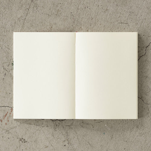 Open 15th anniversary limited edition MD Notebook with embossed Holly Wales design, on a concrete background.