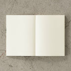 Open 15th anniversary limited edition MD Notebook with embossed Holly Wales design, on a concrete background.
