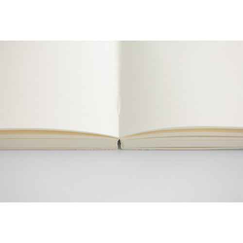 Open 15th anniversary limited edition MD Notebook with embossed Holly Wales design, on a light grey background.