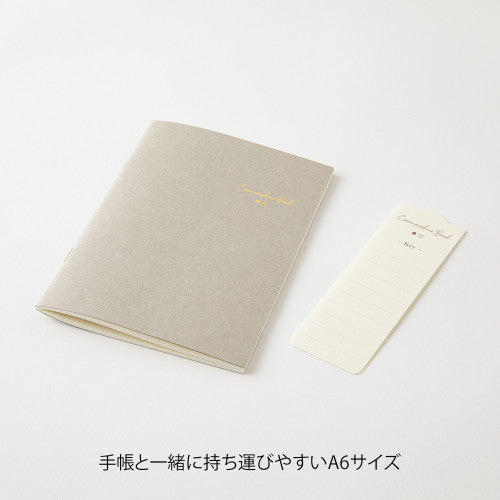Single Midori A6 grey commonplace notebook on a plain background.