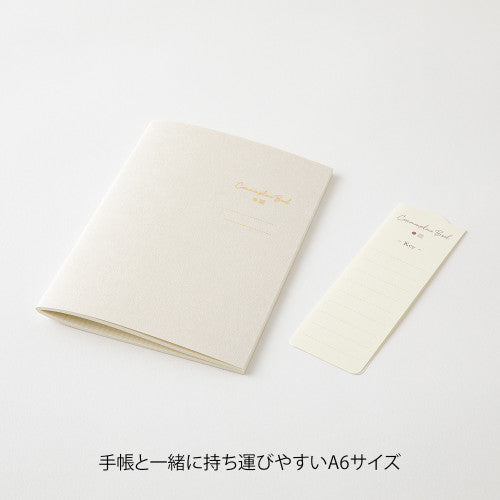 Single Midori A6 beige commonplace notebook on a plain background.