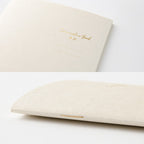 Single Midori A6 beige commonplace notebook on a plain background displayed flat.