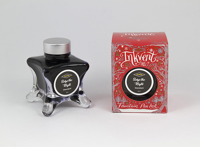 A glass bottle of 50ml Diamine Red Edition Inkvent Seize the Night fountain pen ink next to packaging box, in front of a white background.