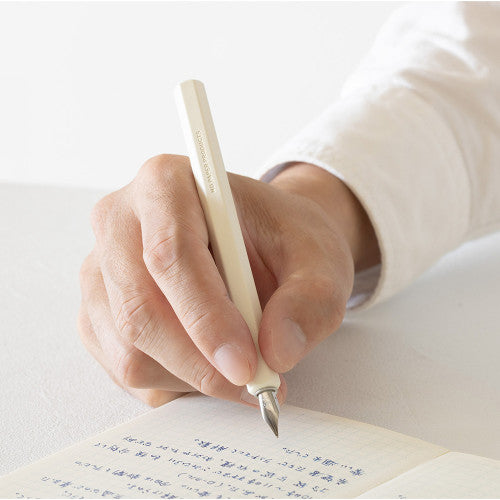 MD Dip Pen in persons hand as they write in an MD notebook.