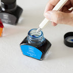 MD Dip Pen being dipped in a Blue Ink MD Fountain Pen Ink Bottle. against a white background.