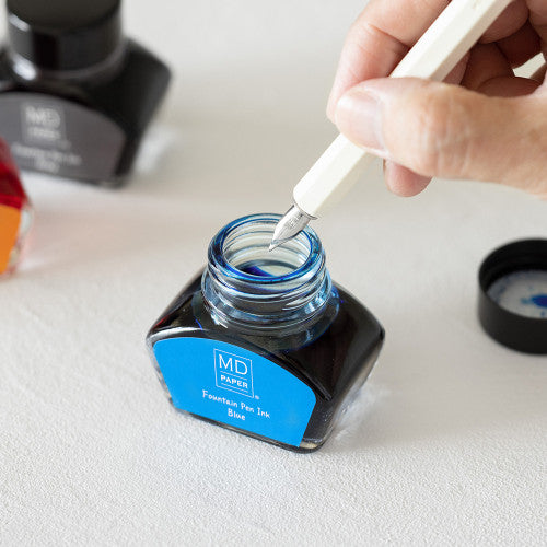 MD Dip Pen being dipped in a Blue Ink MD Fountain Pen Ink Bottle. against a white background.