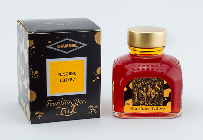 A glass bottle of 80ml Diamine Sunshine Yellow fountain pen ink next to its packaging box, in front of a white background.