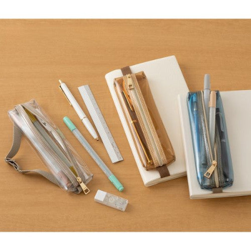 3 colours of Midori Book Band Pen Cases on a desk with notebooks.