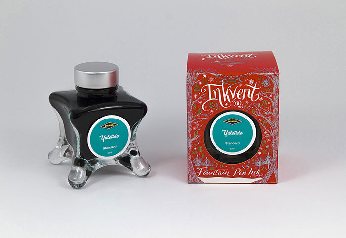 A glass bottle of 50ml Diamine Red Edition Inkvent Yuletide fountain pen ink next to packaging box, in front of a white background.