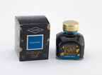 A glass bottle of 80ml Diamine Pelham Blue fountain pen ink next to its packaging box, in front of a white background.