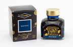 A glass bottle of 80ml Diamine Blue Black fountain pen ink next to its packaging box, in front of a white background.