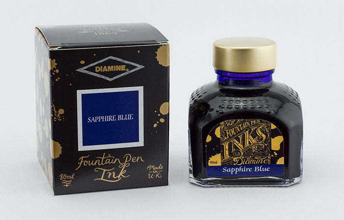 A glass bottle of 80ml Diamine Sapphire Blue fountain pen ink next to its packaging box, in front of a white background.