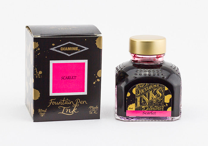 A glass bottle of 80ml Diamine Scarlet fountain pen ink next to its packaging box, in front of a white background.