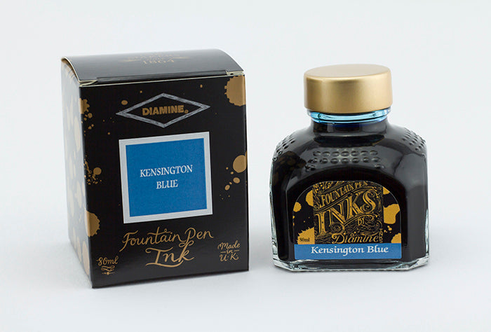 A glass bottle of 80ml Diamine Kensington Blue fountain pen ink next to its packaging box, in front of a white background.