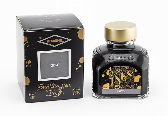 A glass bottle of 80ml Diamine Grey fountain pen ink next to its packaging box, in front of a white background.