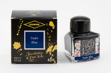 Load image into Gallery viewer, A glass bottle of 40ml Diamine 150th Anniversary Tudor Blue fountain pen ink next to packaging box, in front of a white background.
