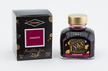 Load image into Gallery viewer, A glass bottle of 80ml Diamine Amaranth fountain pen ink next to its packaging box, in front of a white background.
