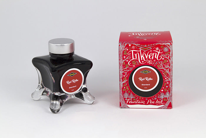 A glass bottle of 50ml Diamine Red Edition Inkvent Red Robin fountain pen ink next to packaging box, in front of a white background.