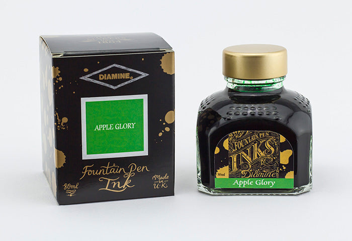 A glass bottle of 80ml Diamine Apple Glory fountain pen ink next to its packaging box, in front of a white background.