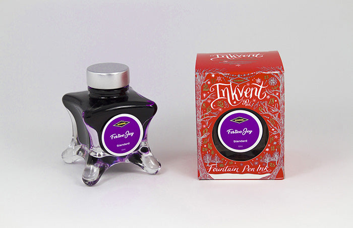 A glass bottle of 50ml Diamine Red Edition Inkvent Festive Joy fountain pen ink next to packaging box, in front of a white background.