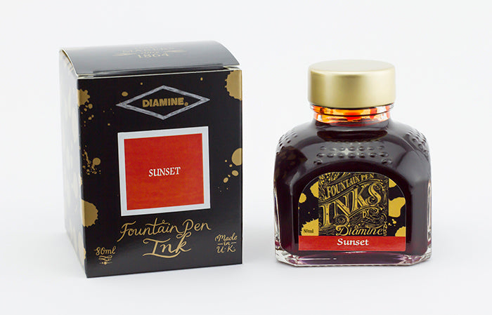 A glass bottle of 80ml Diamine Sunset fountain pen ink next to its packaging box, in front of a white background.