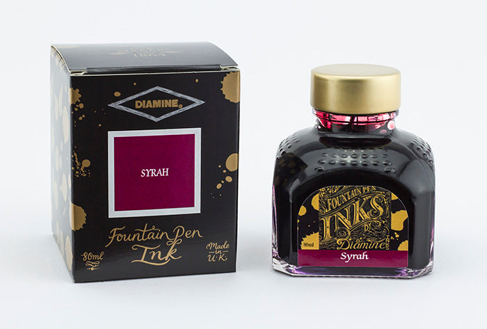 A glass bottle of 80ml Diamine Syrah fountain pen ink next to its packaging box, in front of a white background.