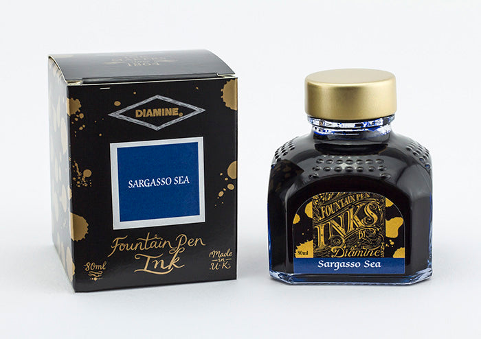 A glass bottle of 80ml Diamine Sargasso Sea fountain pen ink next to its packaging box, in front of a white background.