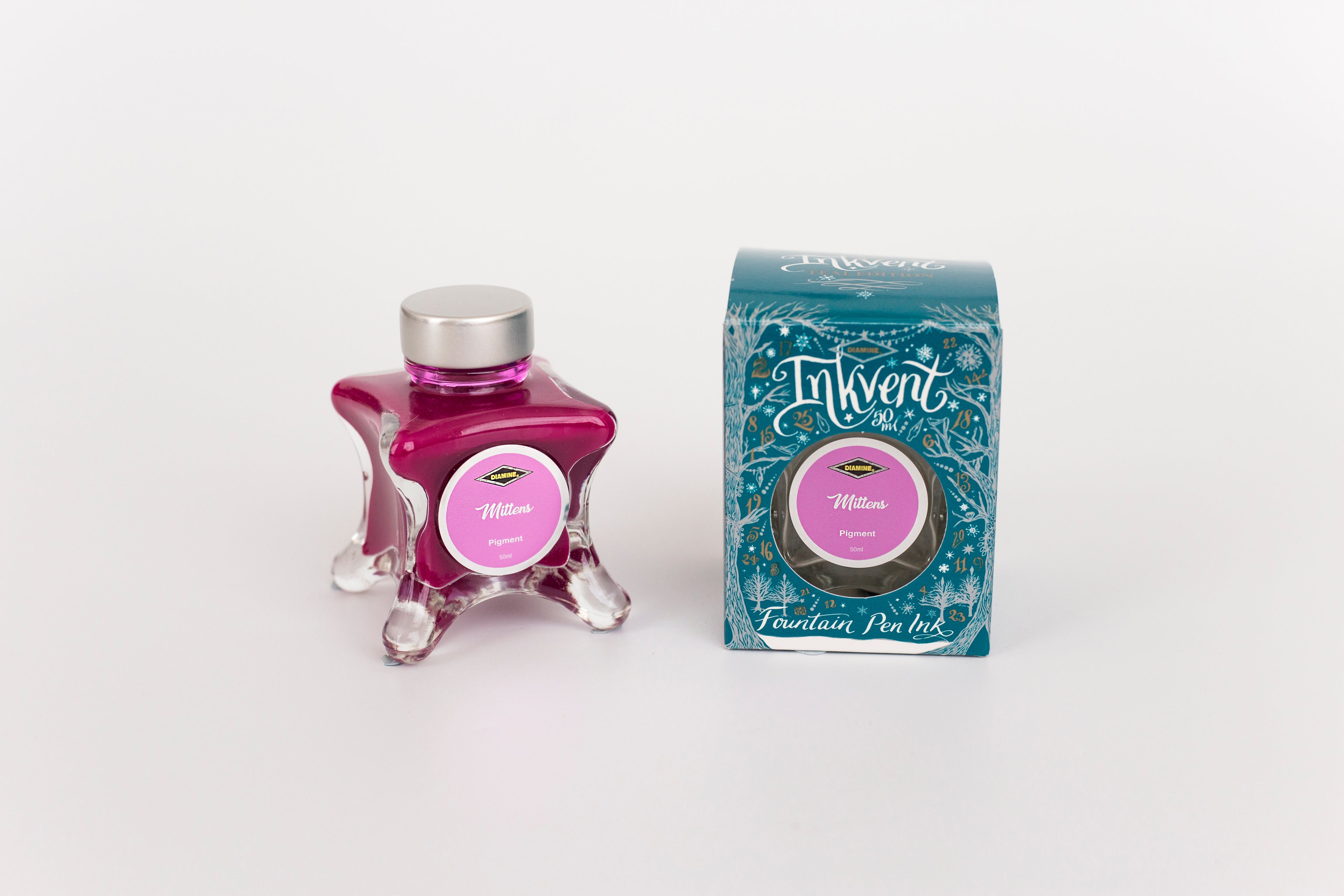 Glass bottle of 50ml Diamine Teal Edition Inkvent Mittens pigment fountain pen ink next to Teal coloured and Christmas-themed packaging box, in front of a white background.