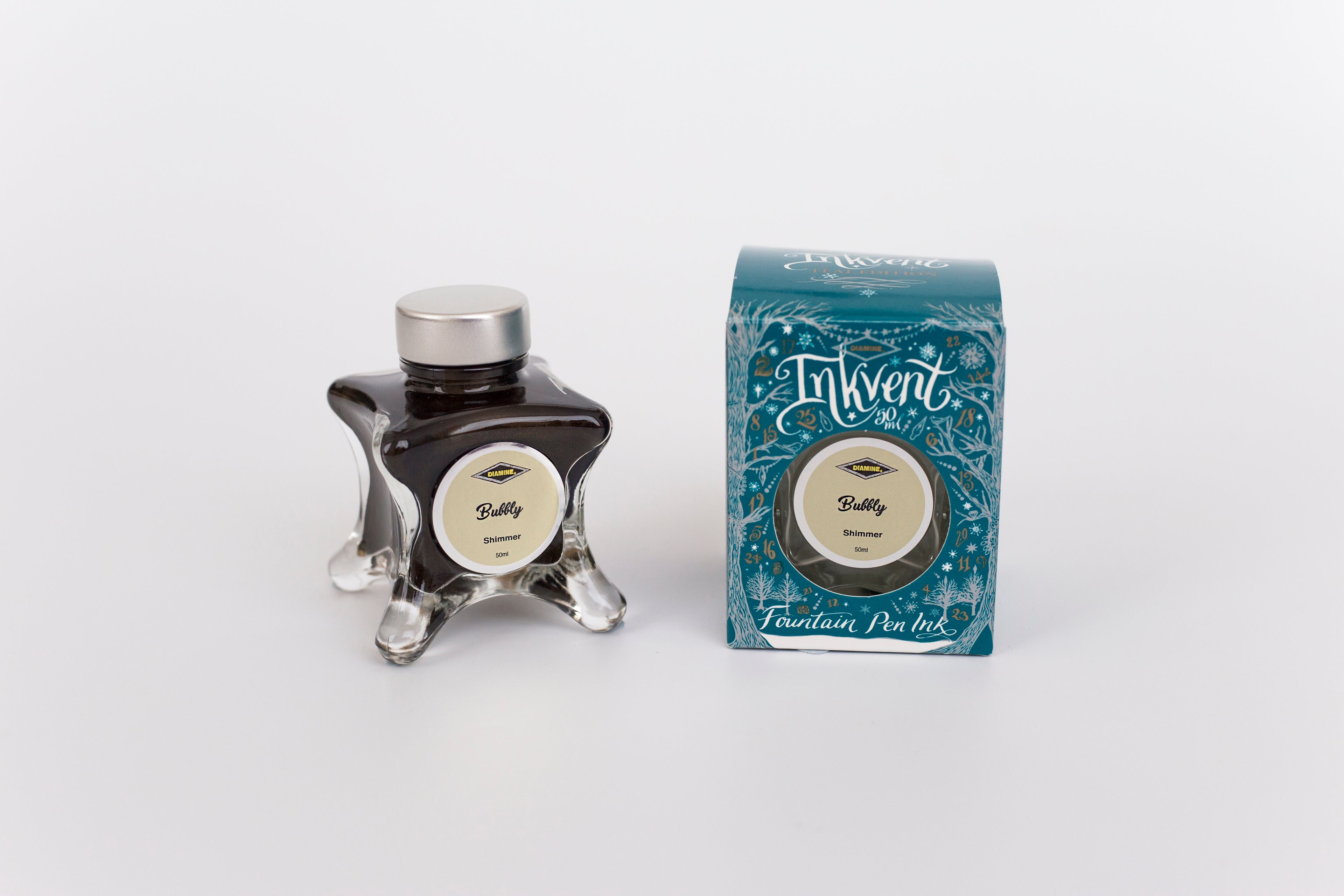 Glass bottle of 50ml Diamine Teal Edition Inkvent Bubbly shimmer fountain pen ink next to Teal coloured and Christmas-themed packaging box, in front of a white background.
