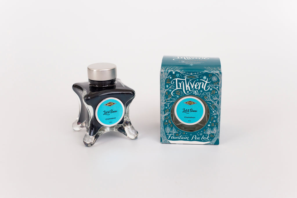 Glass bottle of 50ml Diamine Teal Edition Inkvent Let it Snow chameleon fountain pen ink next to Teal coloured and Christmas-themed packaging box, in front of a white background.