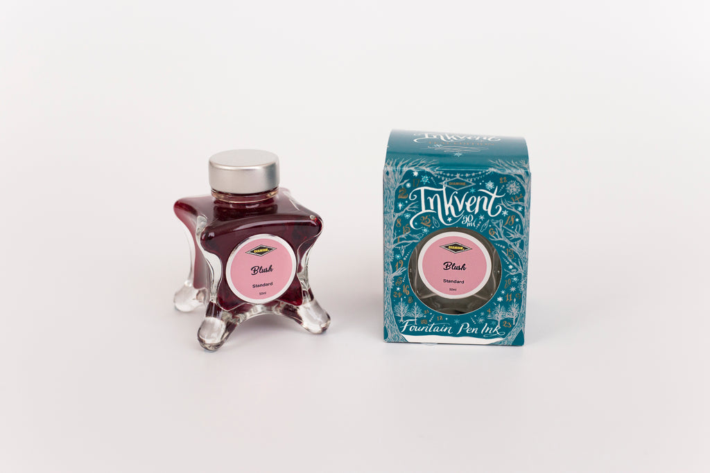 Glass bottle of 50ml Diamine Teal Edition Inkvent Blush fountain pen ink next to Teal coloured and Christmas-themed packaging box, in front of a white background.