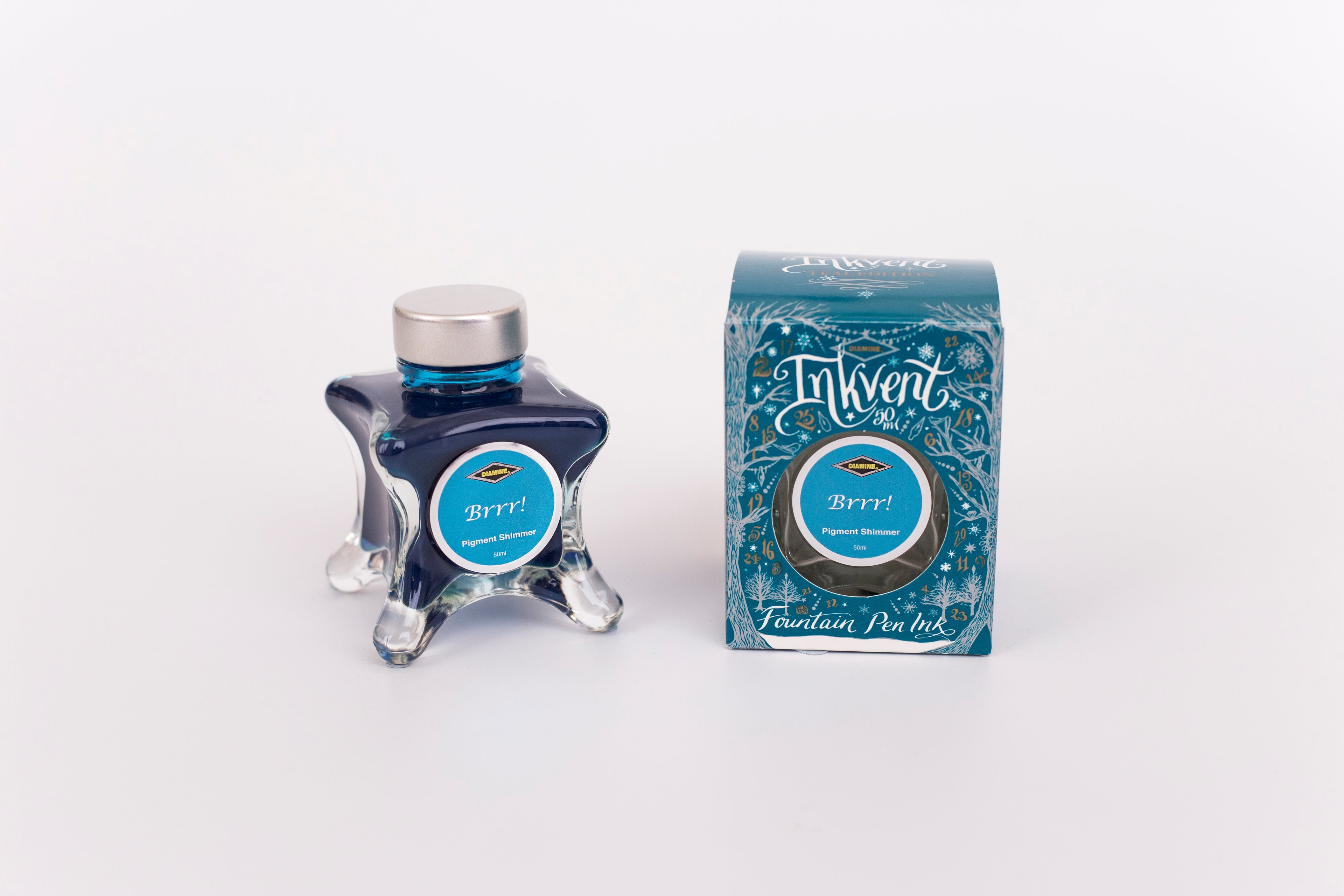 Glass bottle of 50ml Diamine Teal Edition Inkvent BRRR! pigment shimmer fountain pen ink next to Teal coloured and Christmas-themed packaging box, in front of a white background.