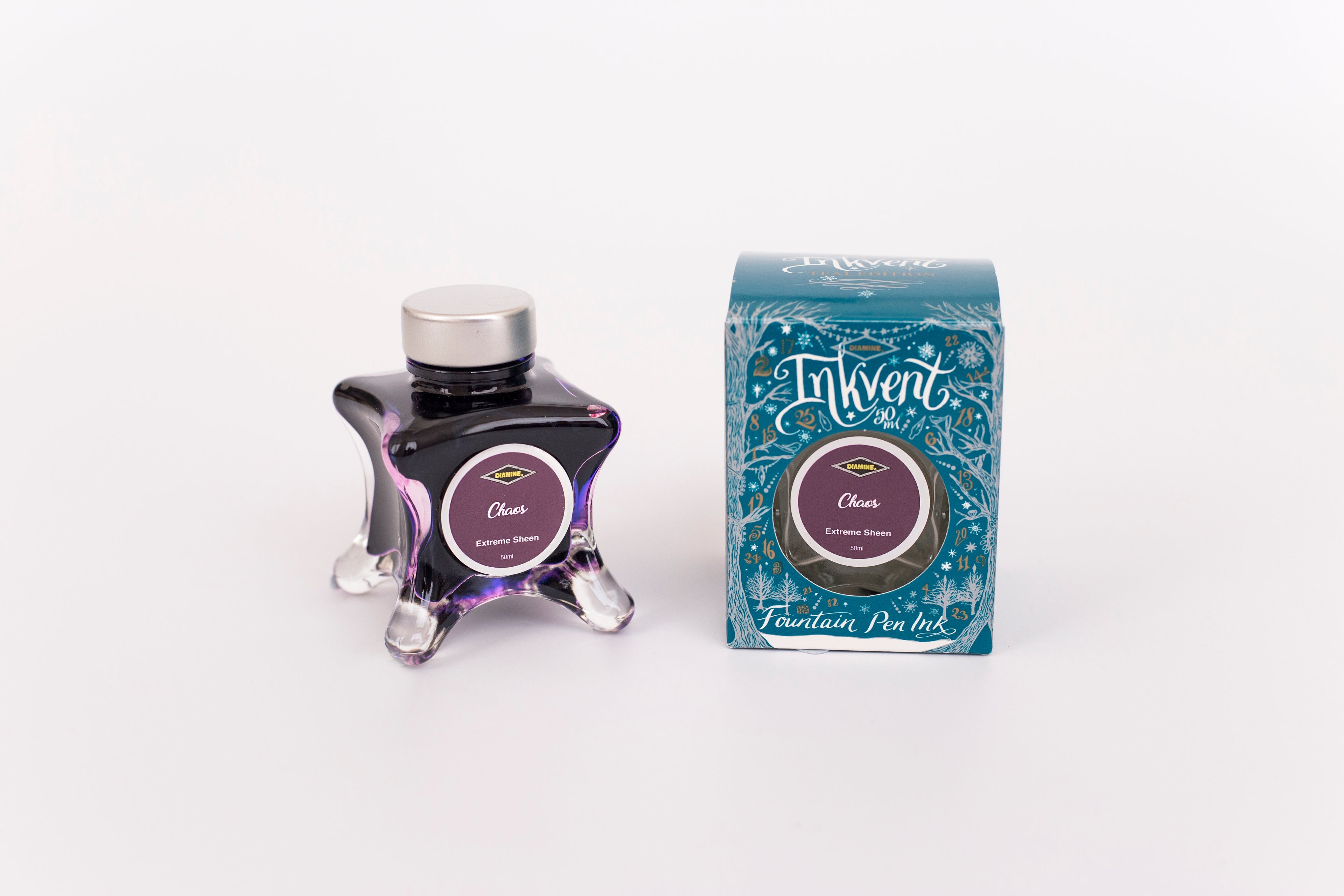 Glass bottle of 50ml Diamine Teal Edition Inkvent Chaos fountain pen ink next to Teal coloured and Christmas-themed packaging box, in front of a white background.