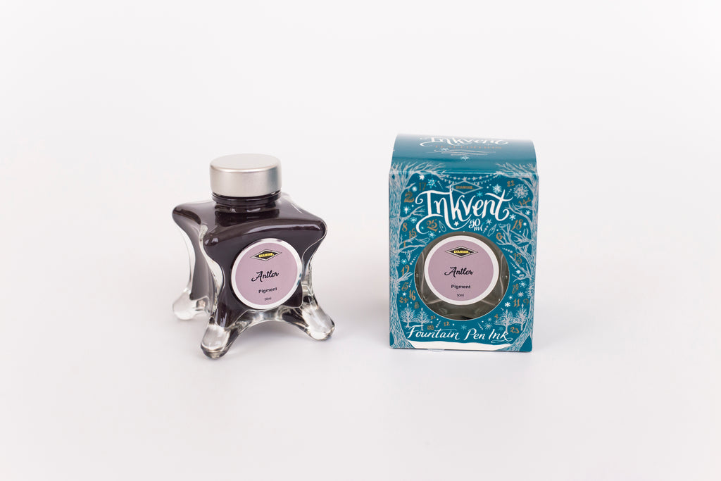 Glass bottle of 50ml Diamine Teal Edition Inkvent Antler pigment fountain pen ink next to Teal coloured and Christmas-themed packaging box, in front of a white background.