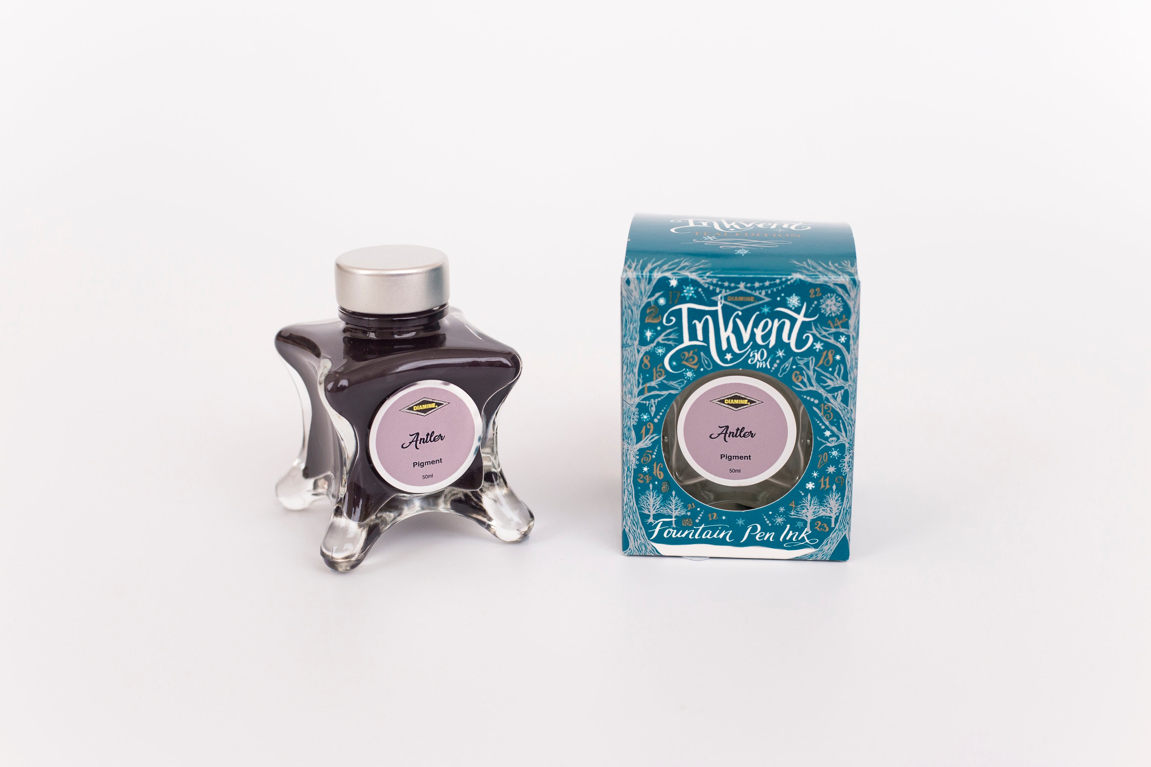 Glass bottle of 50ml Diamine Teal Edition Inkvent Antler pigment fountain pen ink next to Teal coloured and Christmas-themed packaging box, in front of a white background.