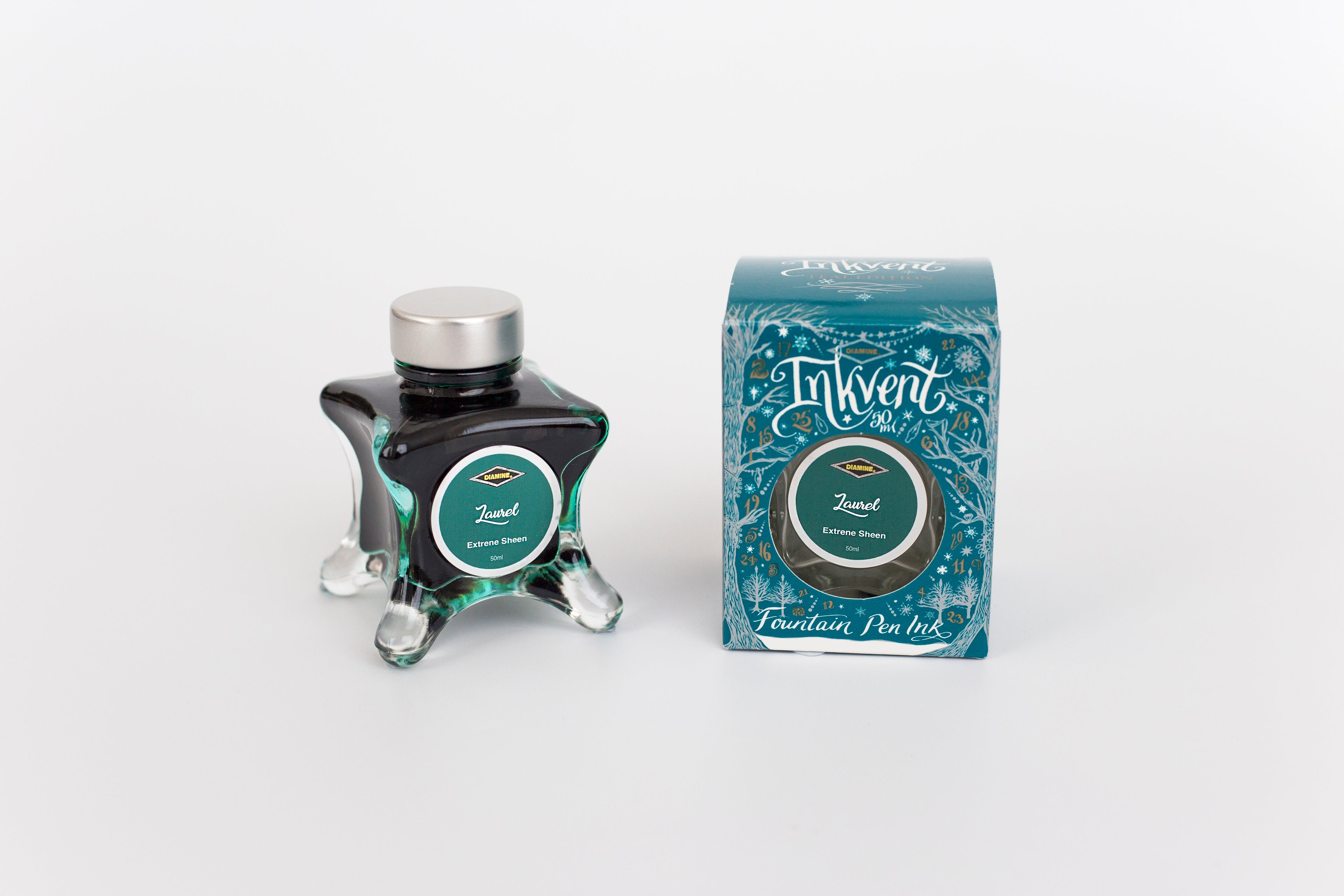 Glass bottle of 50ml Diamine Teal Edition Inkvent Laurel extreme sheen fountain pen ink next to Teal coloured and Christmas-themed packaging box, in front of a white background.