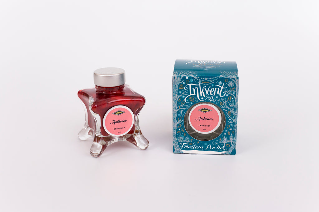 Glass bottle of 50ml Diamine Teal Edition Inkvent Ambience fountain pen ink next to Teal coloured and Christmas-themed packaging box, in front of a white background.