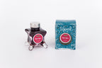 Glass bottle of 50ml Diamine Teal Edition Inkvent Ruby Taffeta fountain pen ink next to Teal coloured and Christmas-themed packaging box, in front of a white background.