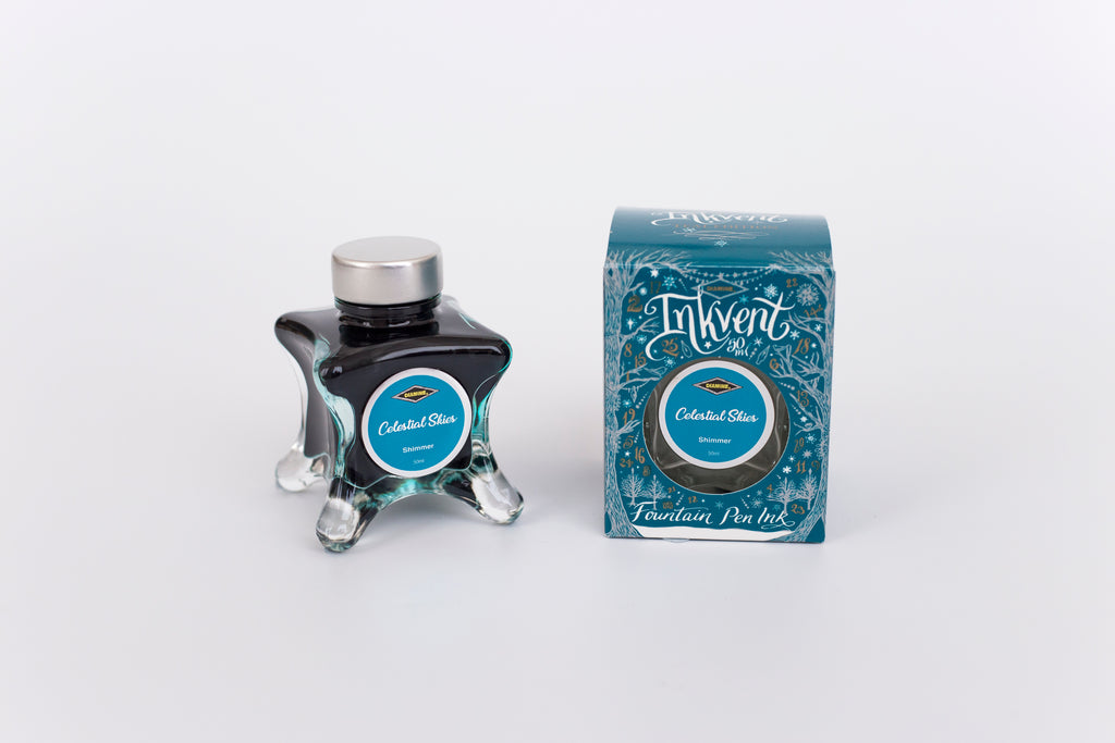Glass bottle of 50ml Diamine Teal Edition Inkvent Celestial Skies fountain pen ink next to Teal coloured and Christmas-themed packaging box, in front of a white background.