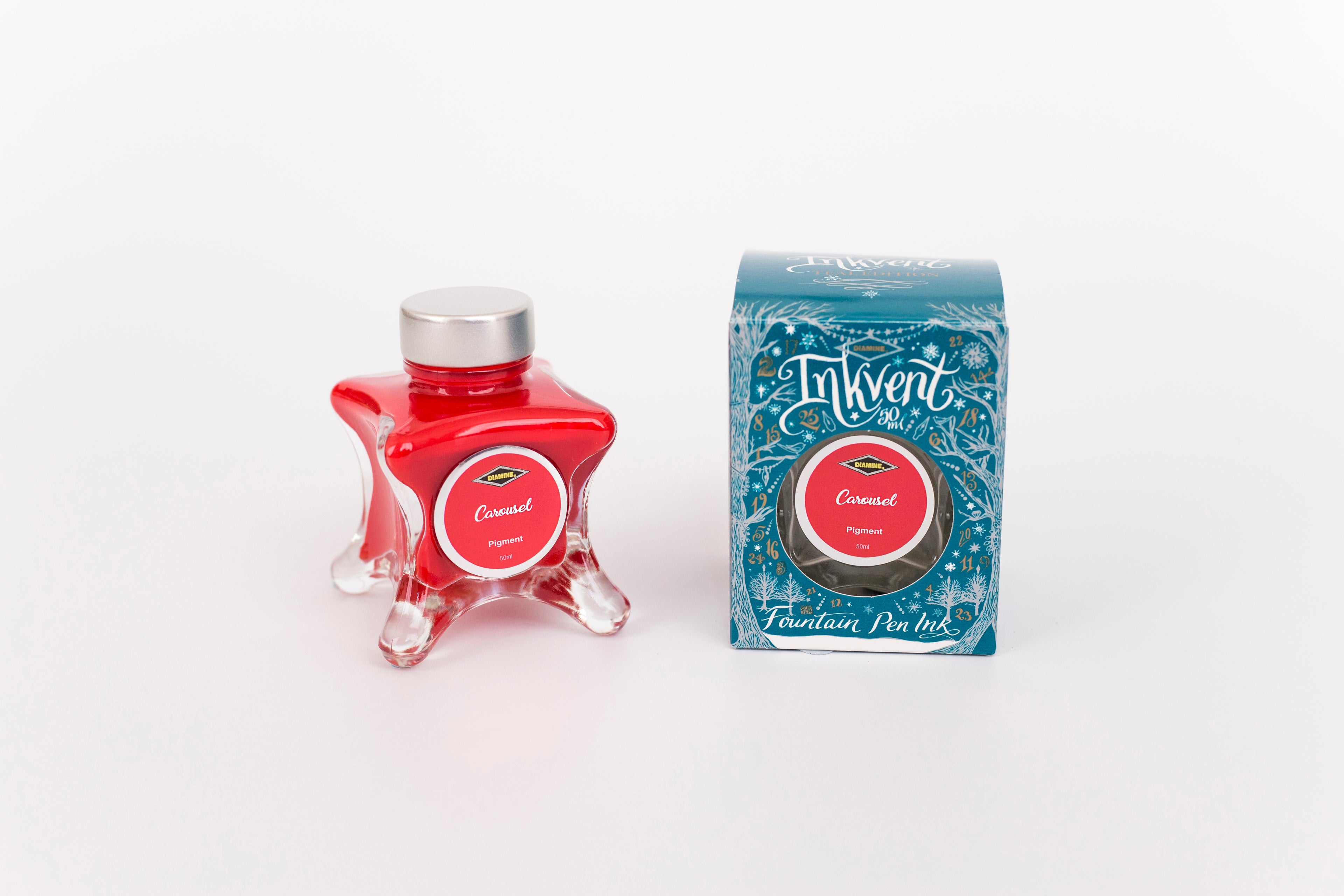 Glass bottle of 50ml Diamine Teal Edition Inkvent Carousel fountain pen ink next to Teal coloured and Christmas-themed packaging box, in front of a white background.