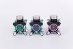 Group of three glass bottles of 50ml Diamine Teal Edition Inkvent extreme sheen fountain pen ink, Laurel, Dream Catcher & Chaos. Sitting in front of a white background.